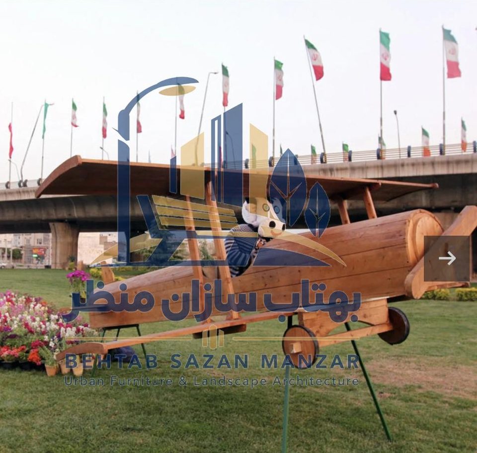 المان تزئینی هواپیمای دوباله چوبی در فضای سبز کنار گل‌کاری